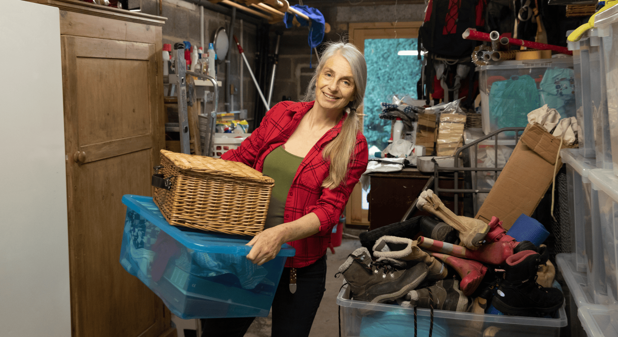 Frau entrümpelt Keller und sortiert Gegenstände in Kisten beim Haus entrümpeln